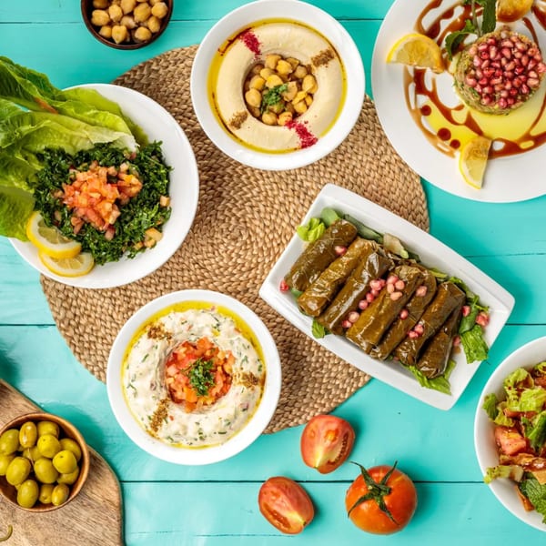 Overhead view of a vibrant Lebanese mezze spread including hummus, tabbouleh, and stuffed grape leaves.